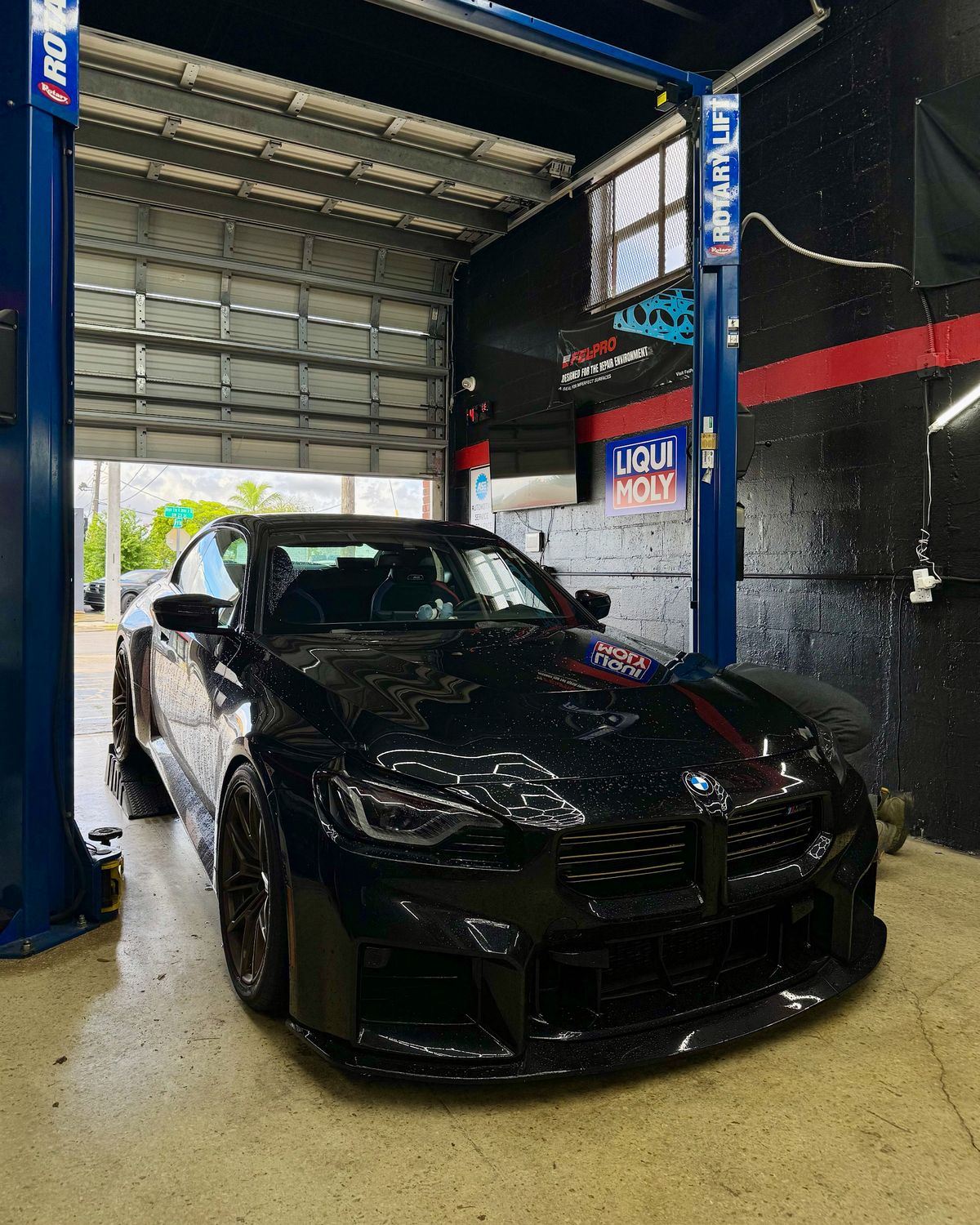 Black BMW M2 Competition parked in the bay under the Liqui Moly sign
